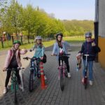 Czworo uczniów na rowerze koło szkoły