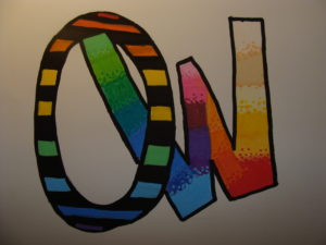 Praca przedstawia dwie zachodzące za siebie litery "O" z "W". Litery ozdobione są skośnymi kolorowymi pasami.