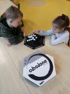 2 dzieci siedzi przy stole i gra w grę Abalone.