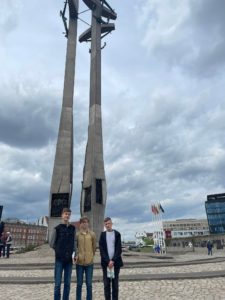 Trzech chłopców stoi na tle pomnika Trzech Krzyży w Gdańsku