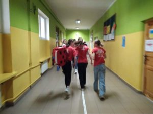 Trzyosobowa drużyna SP 47 w Gdańsku w czerwonych koszulkach z wyposażoną apteczką pędzi korytarzem z kierunku upozorowanego zdarzenia.