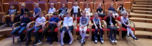 Uczniowie klasy 1a elegancko ubrani, siedzą na fotelach w sali koncertowej Polskiej Filharmonii Bałtyckiej. 