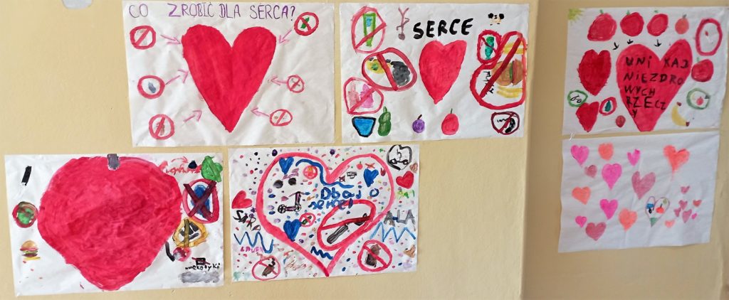 Na ścianie szkolnego korytarza wisi 6 plakatów z sercami wykonanych przez klasy młodsze, które głoszą hasła promujące zdrowy styl życia. 