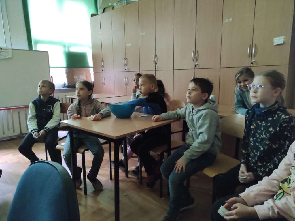 Uczniowie klas młodszych na piątkowym seansie filmowym, na stole misa z popokornem