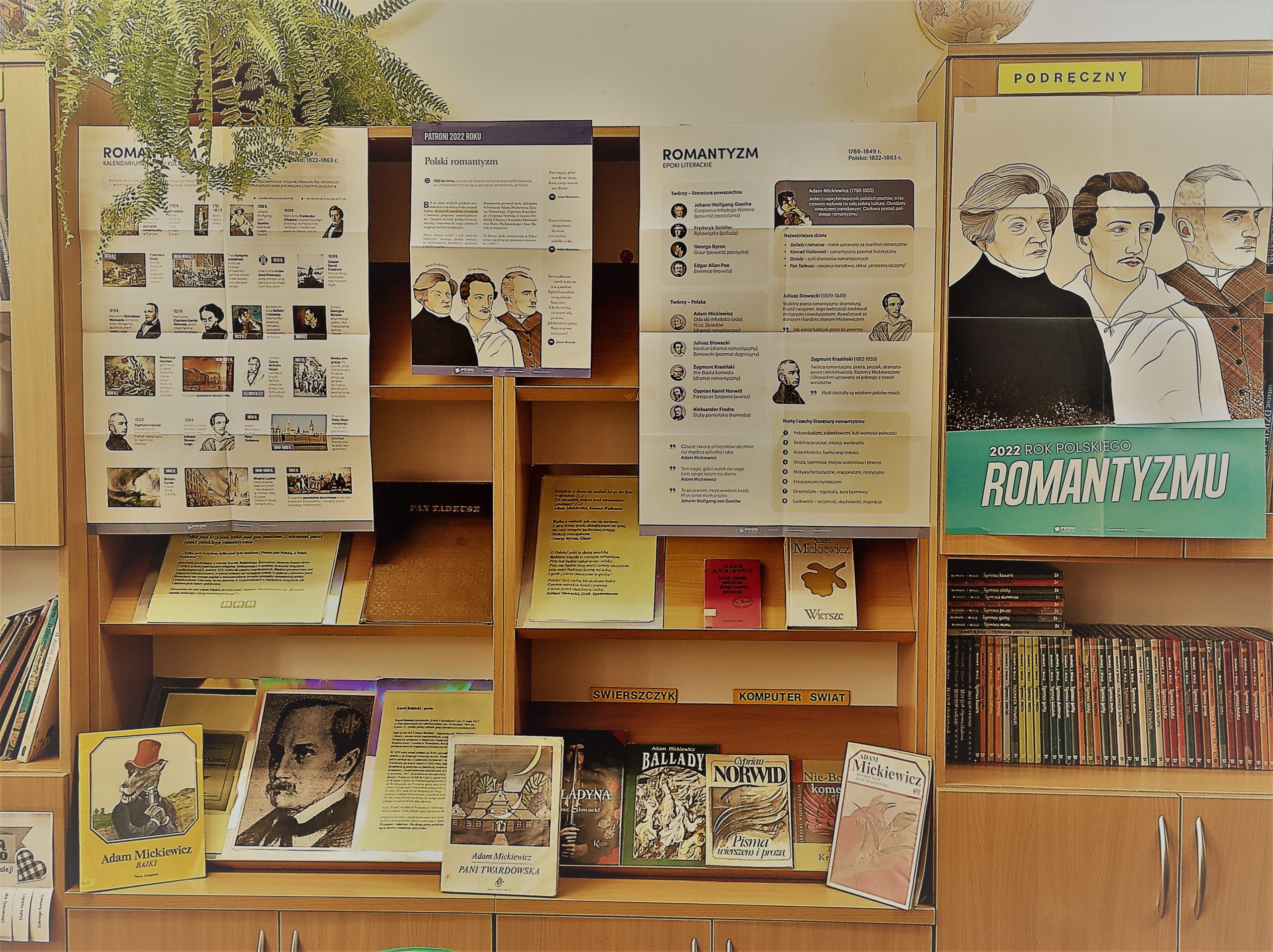 Plakaty, zdjęcia oraz książki na wystawie polskiego romantyzmu w bibliotece szkolnej.