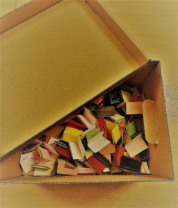 otwarte, ozdobne pudełko wewnątrz kolorowe złożone karteczki na których są umieszczone tytuły książek.