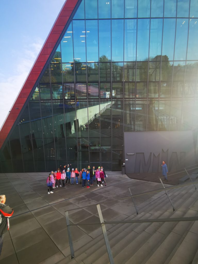 Grupa uczniów stoi przed wejściem do Muzeum II Wojny Światowej.