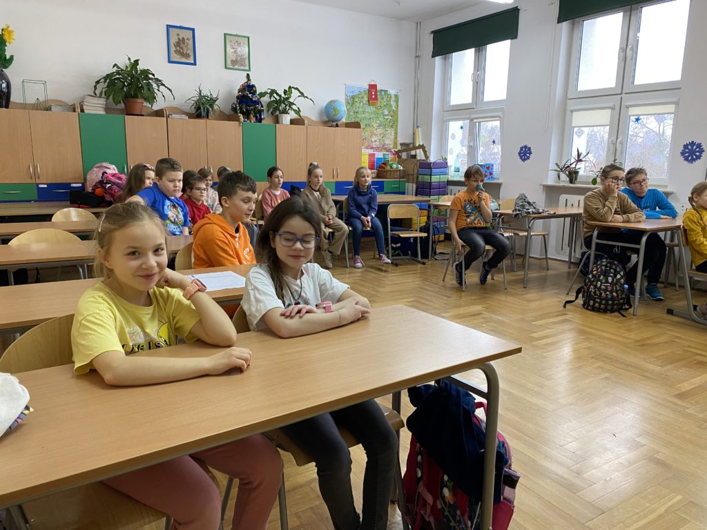 Uczniowie siedzący w ławkach w sali lekcyjne