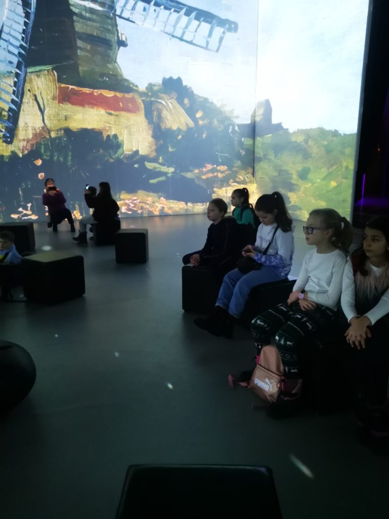 uczniowie siedzą w hali Amber Expo i oglądają prezentację na temat Van Gogha