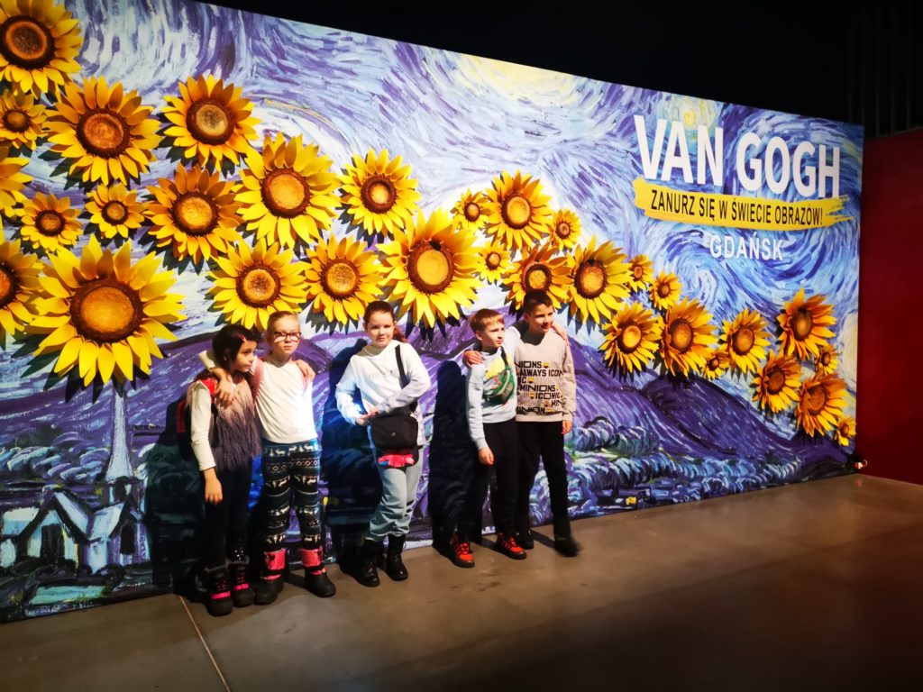 pięcioro dzieci stoi, w tle słoneczniki i napis Van Gogh zanurz się w świecie obrazów