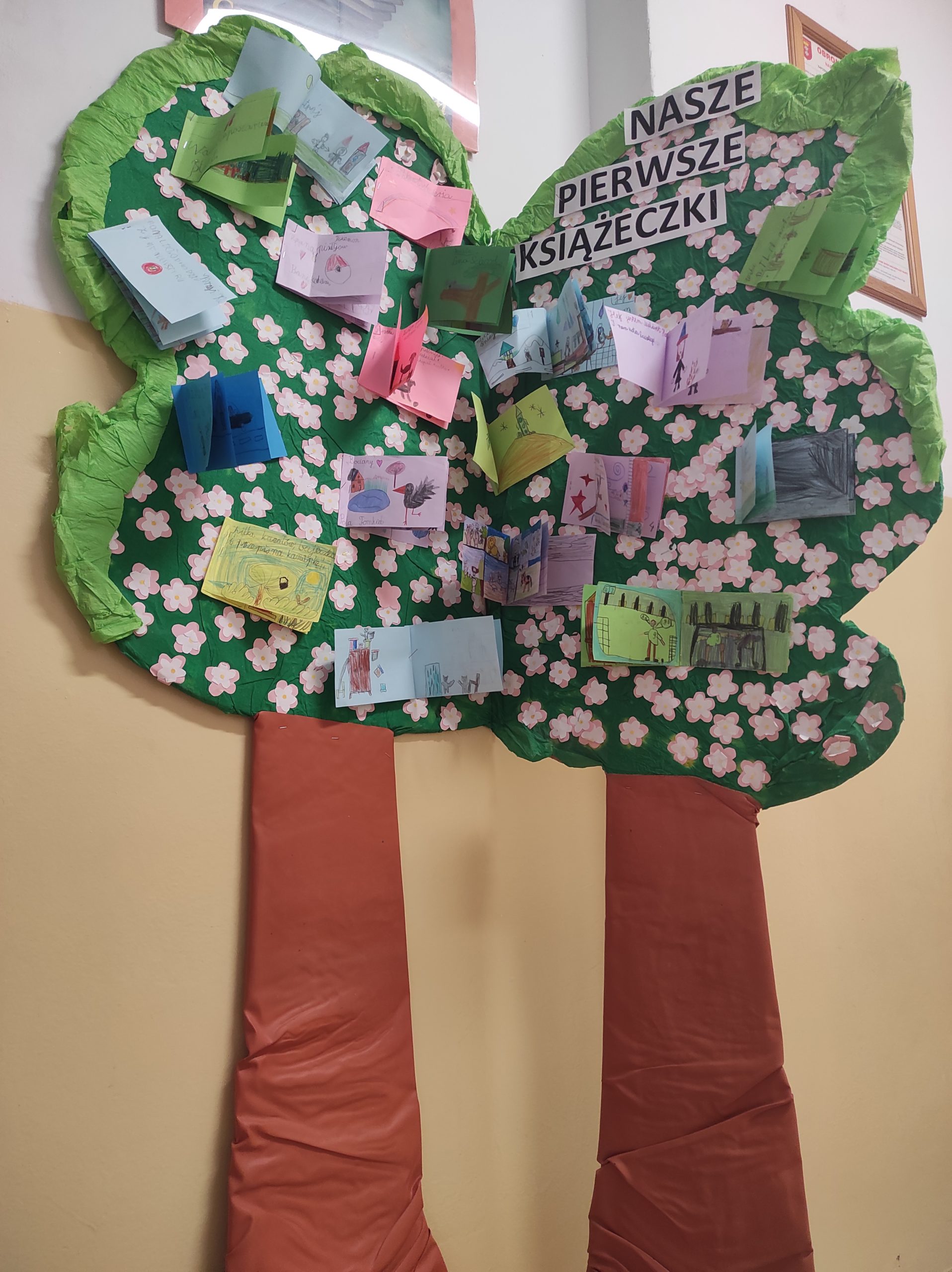 Kartonowe, kolorowe drzewo z przyczepionymi malutkimi książeczkami, które wykonały dzieci z pierwszej klasy