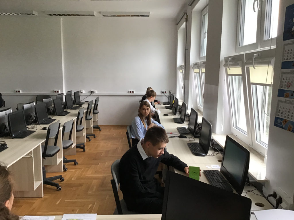 Czworo uczniów w sali lekcyjnej siedzą przed komputerami