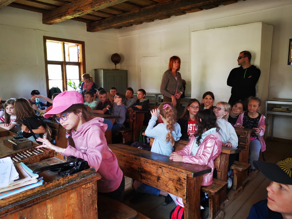 Dzieci siedzą w ławkach w starej kaszubskiej szkole.