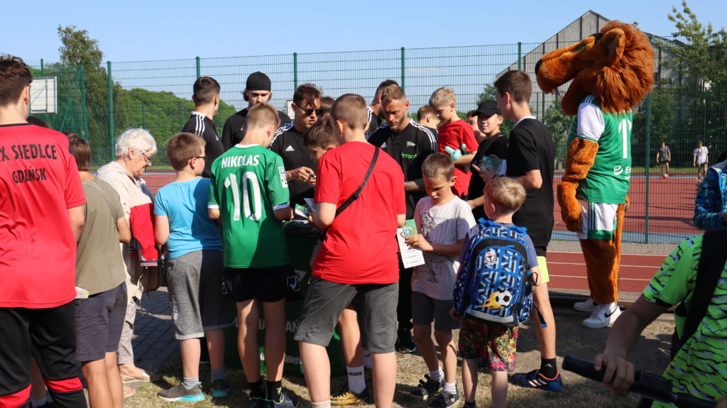 Uczniowie, którzy otrzymują autografy od piłkarzy klubu piłkarskiego „Lechia”.