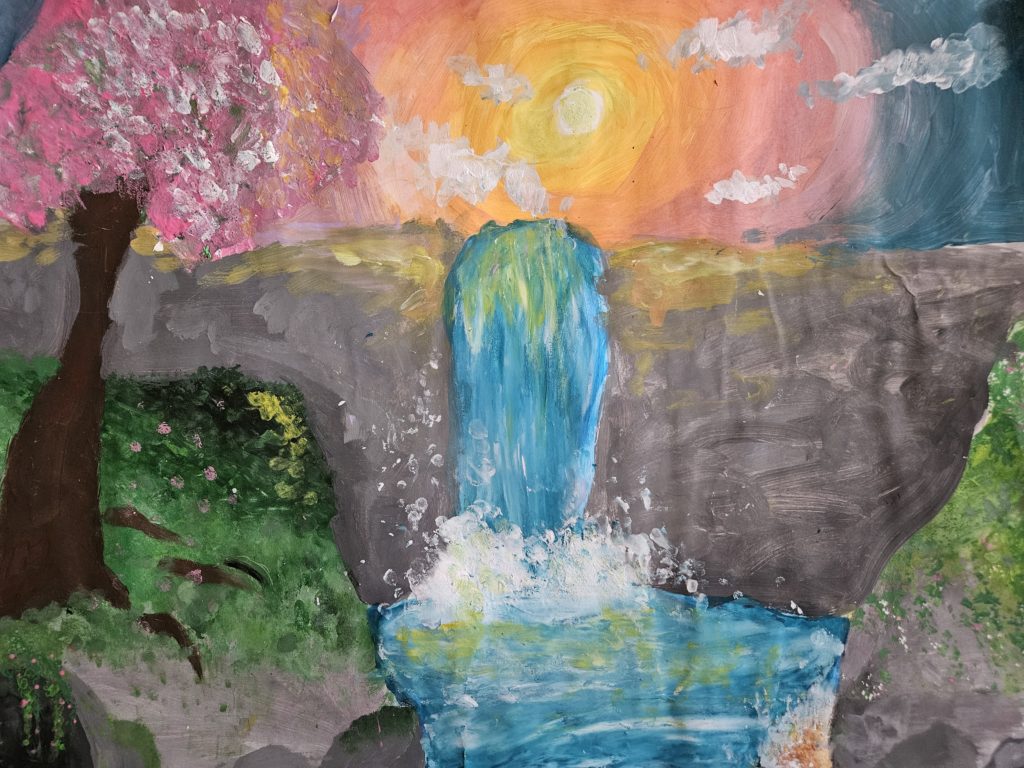 Praca przedstawia letni krajobraz. Po lewej stronie drzewo, centralnie niebieski wodospad, po prawej stronie skarpa. Centralnie szara skała ze spadającą wodą. Na niebie pomarańczowo-różowe słońce