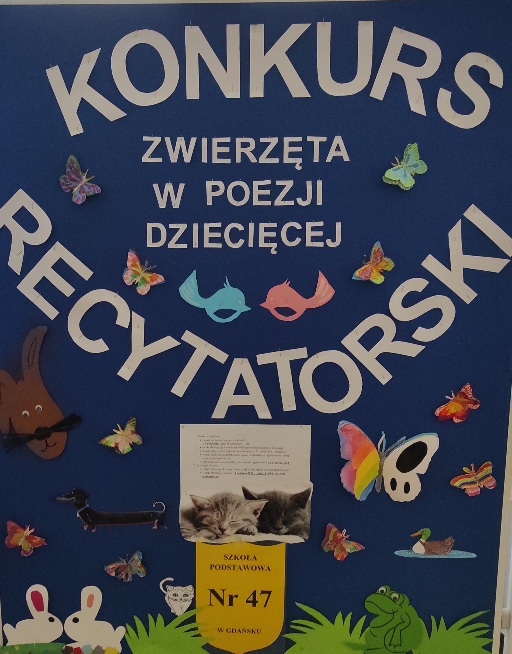 Tablica informacyjna z napisem KONKURS RECYTATORSKI "ZWIERZĘTA W POEZJI DZIECIĘCEJ" i kolorowymi obrazkami zwierząt.