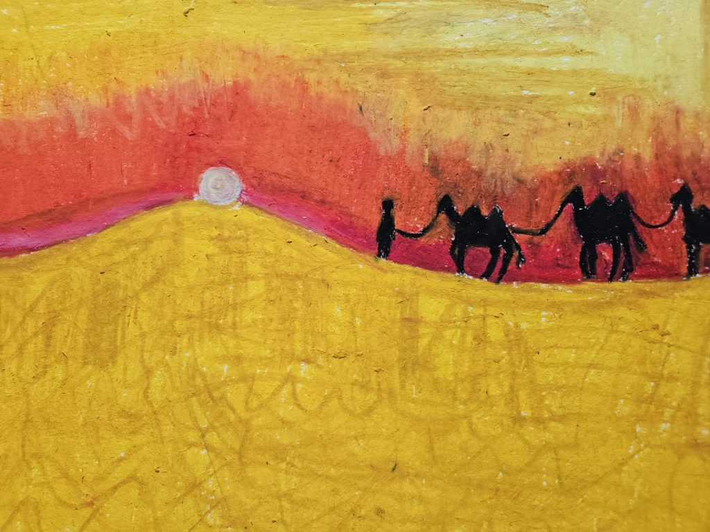 Na pierwszym planie żółte piaski pustyni. Na horyzoncie, po prawej stronie sylwetki człowieka prowadzacego trzy wiełądy. Na horyzoncie zachodzące słońce. Całość w gamie barw żółtych i pomarańczowych