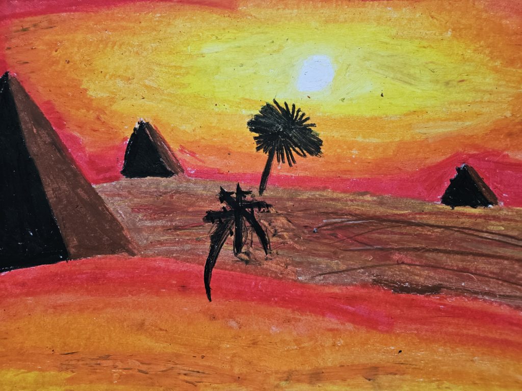 Na pierwszym planie czarne sylwetki to po lewej stronie palma a za nią zarys piramid. Na drugim planie sylwetki palmy i ostrosłupowej piramidy. Na horyzoncie zachodzące słońce. Całość w gamie barw żółtych i pomarańczowych