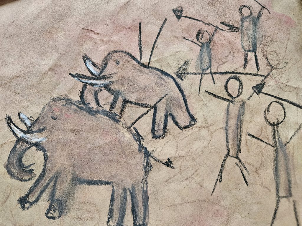 Praca inspirowana malarstwem paleolitu ze sceną z polowania. Na pierwszym planie, po prawej stronie zarysy ludzi, a po prawej uciekajacych mamutów. Na drugim planie podobnie