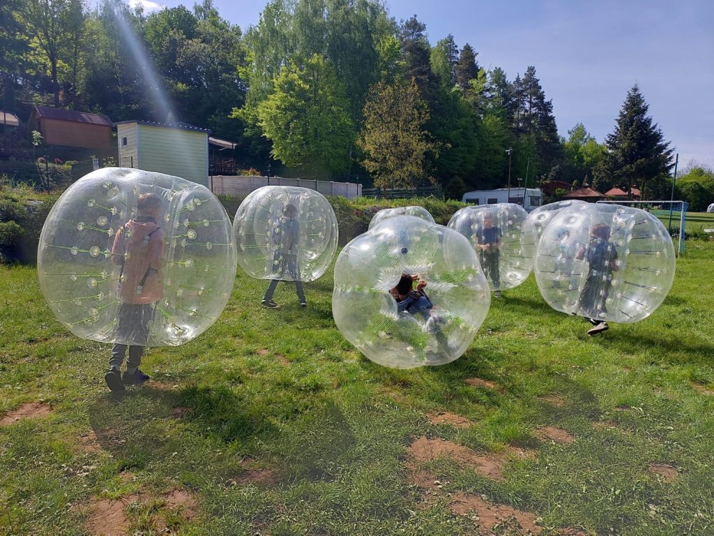 Na polu campingowym, na łące uczniowie klas bawią się w siedmiu, przezroczystych piłkach Bomper Ball.
