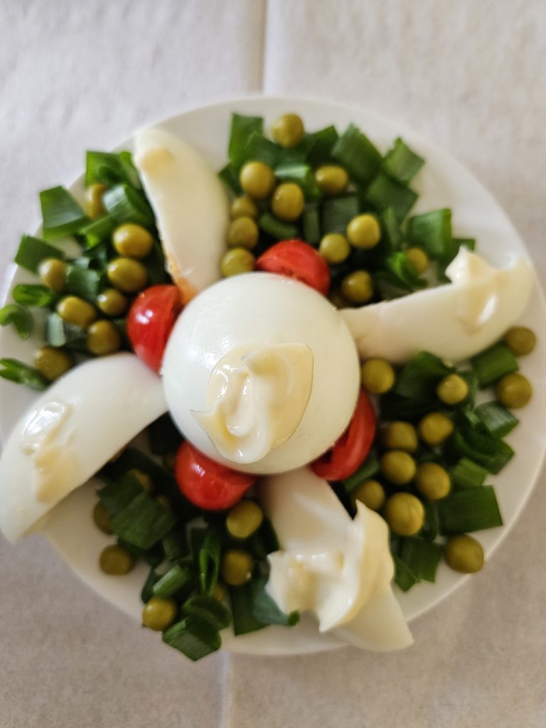 Na talerzykach ułożone i udekorowane warzywami ugotowane jajeczka