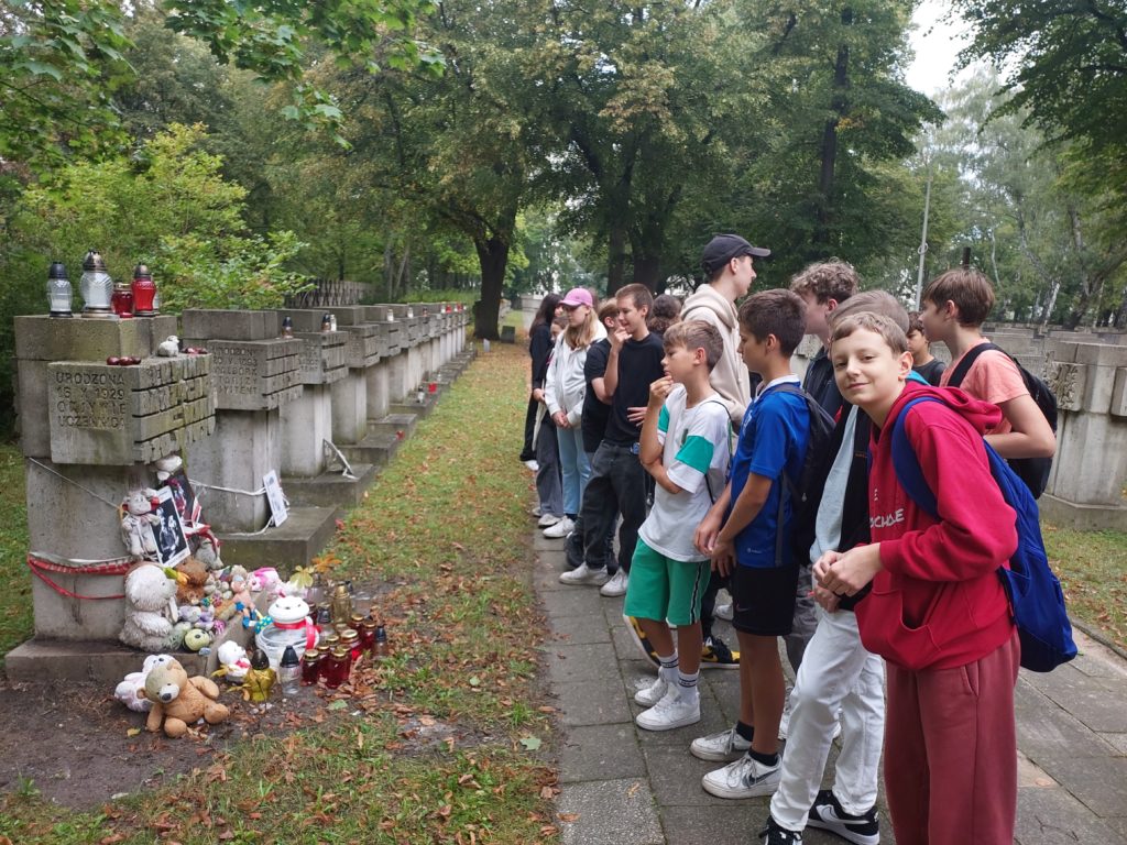 Grupa uczniów klas 7 ze Szkoły Podstawowej nr 47 w Gdańsku stoi na Cmenatarzu Ofiar Hitleryzmu przed grobem Erwiny Barzychowskiej.