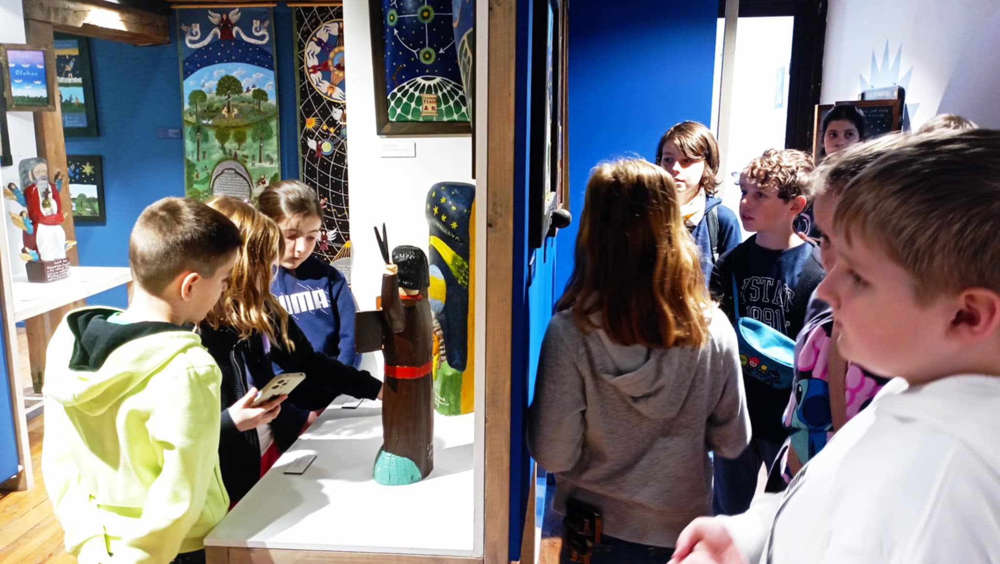 Na tle wyeksponowanych rzeźb i obrazów wystawy „Chełmowskiego wszechświat wyobrażony” stoją zaciekawieni uczniowie klasy 3c.