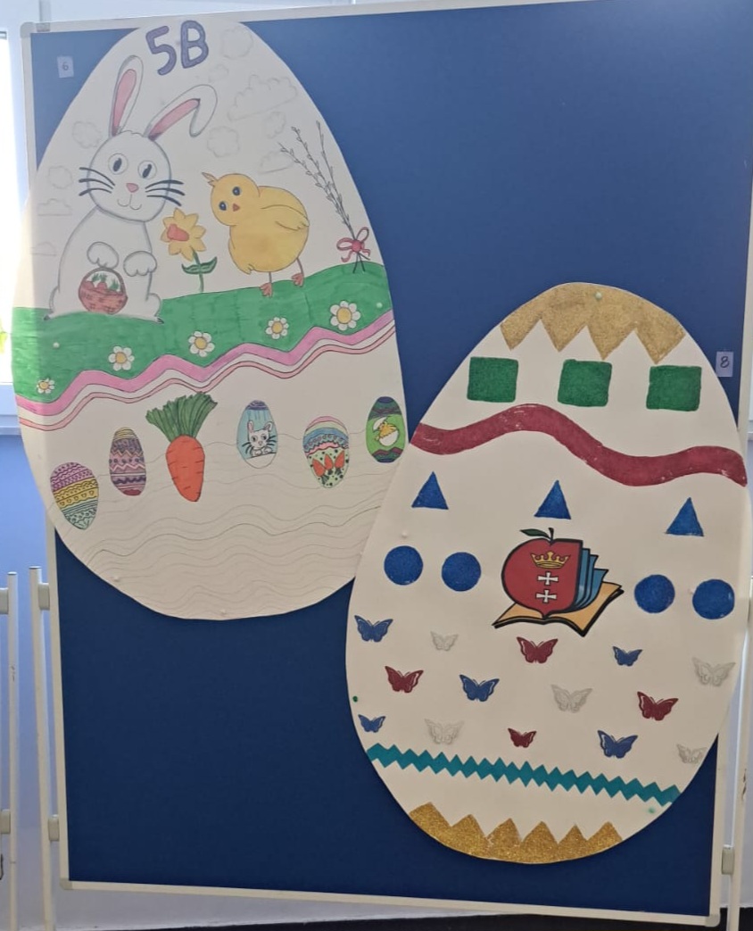 Widoczne 2 duże ozdobne jajka wielkanocne wykonane z papieru, umieszczone na tablicy.