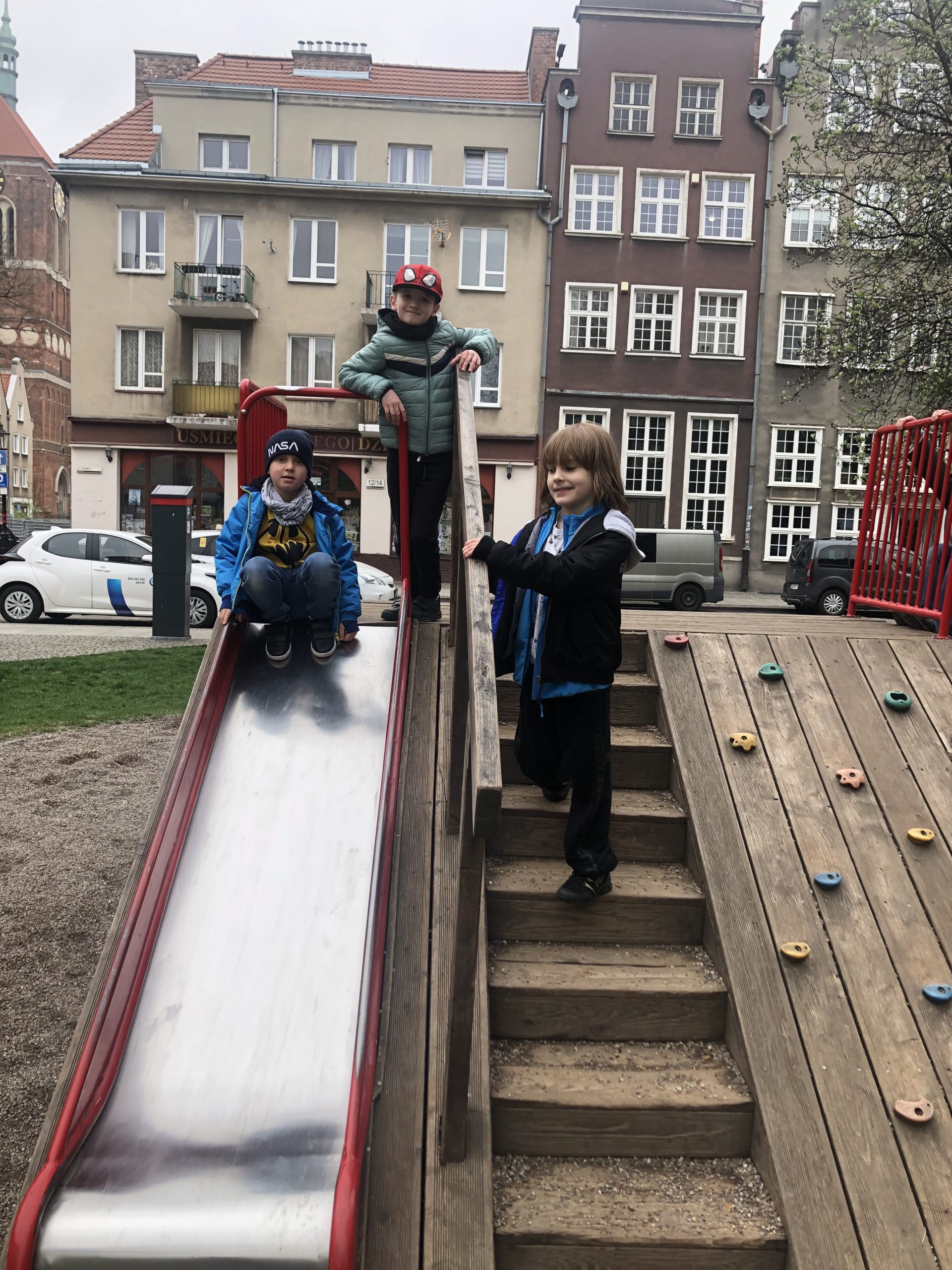 Trzech chłopców stoi na zjeżdżalni.