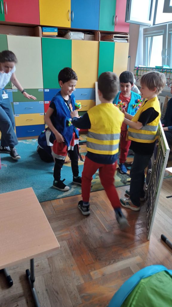 4 dzieci przebrane w kamizelki, stoi do siebie przodem