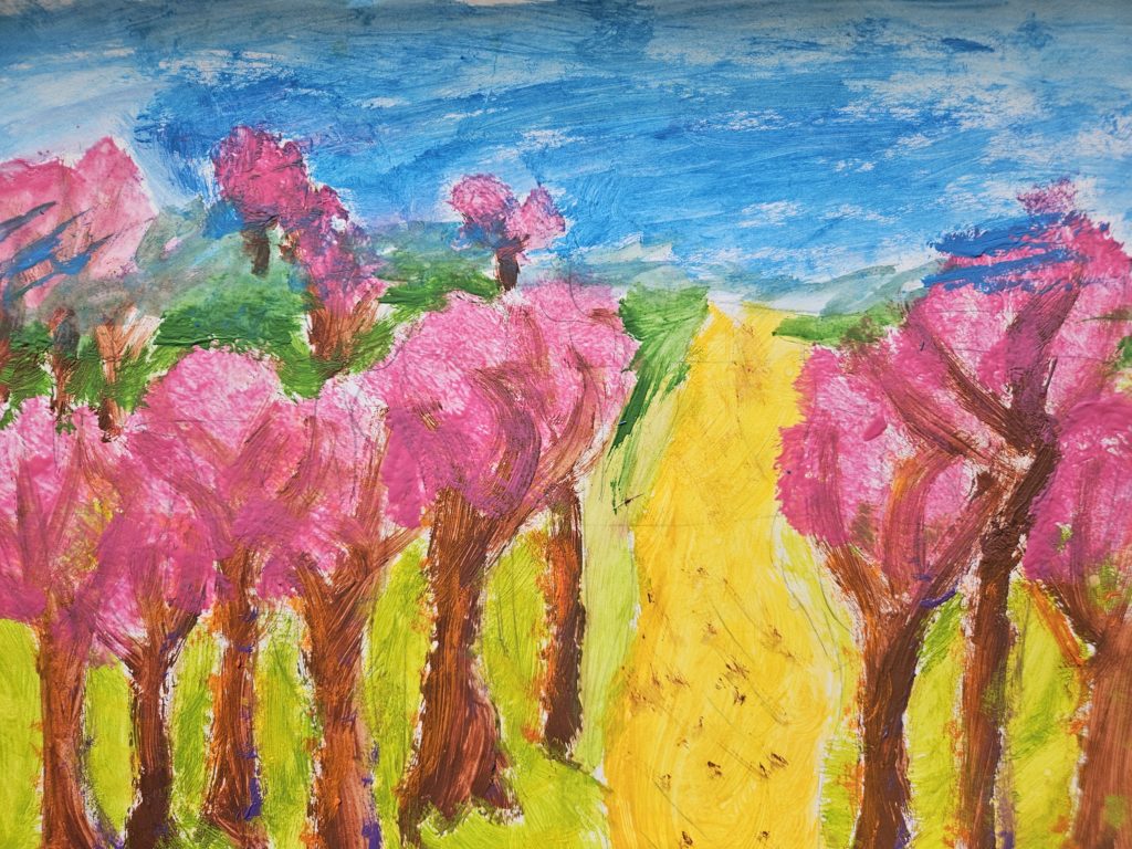 Na pracy żółta droga a po bokach różowo kwitnące drzewka