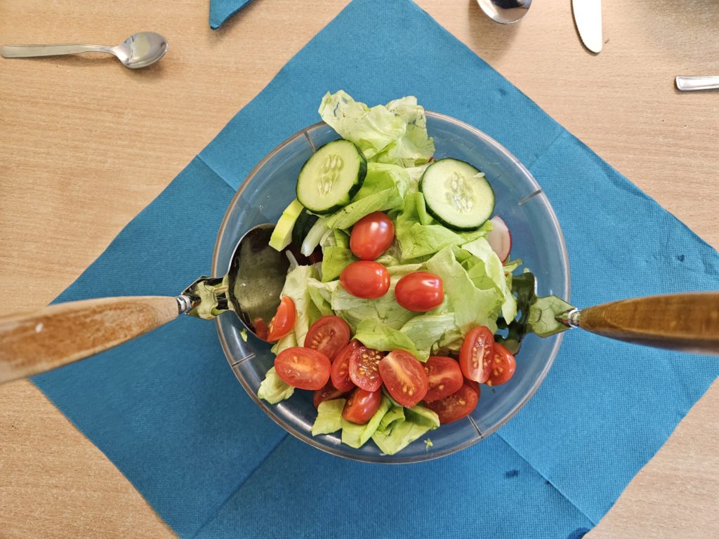 Na granatowej serwetce w miseczce sałatka z pomidorków, sałaty i ogórków.