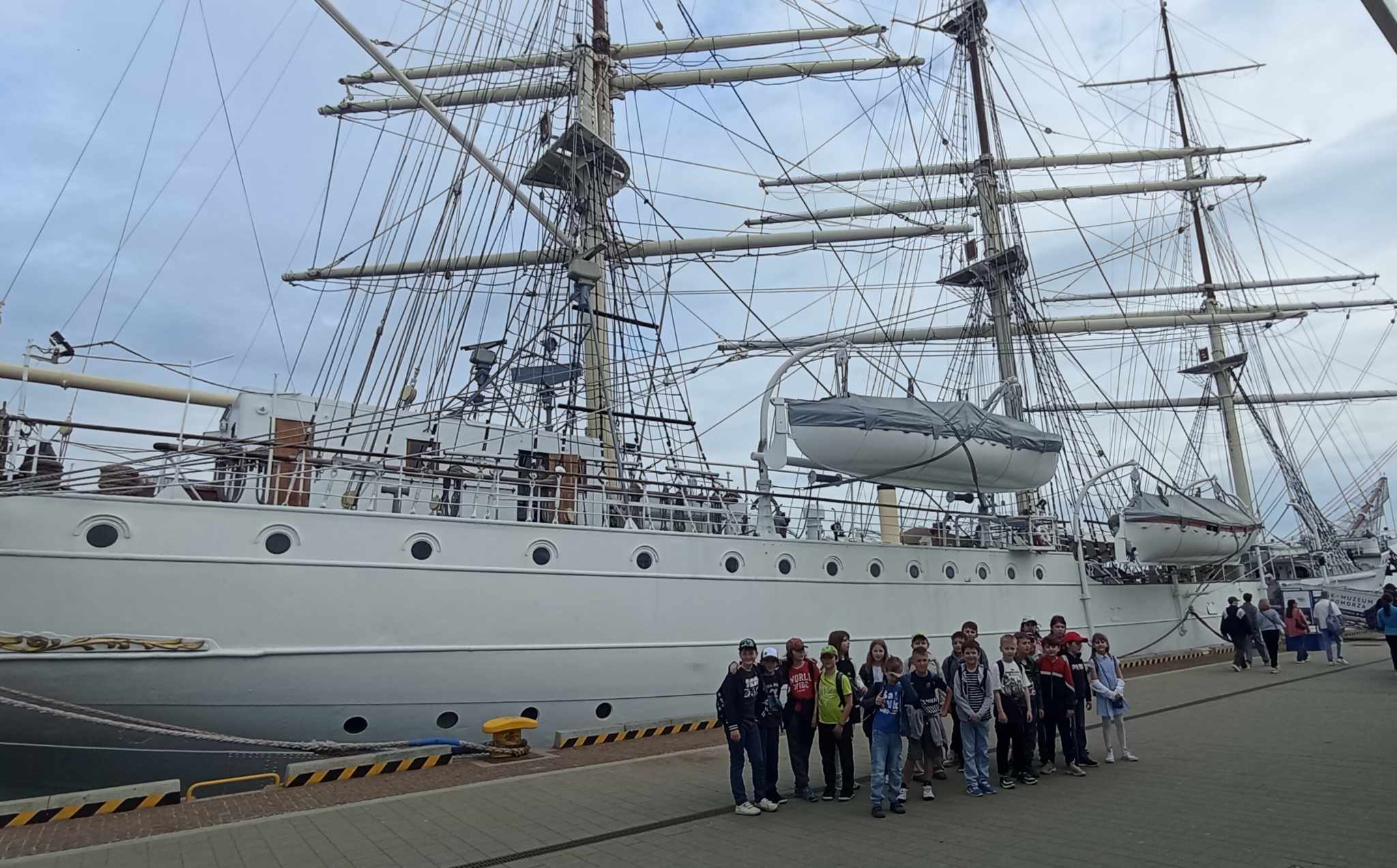 Na tle statku Dar Pomorza ponad dwudziestoosobowa grupa uczniów klasy 3c.