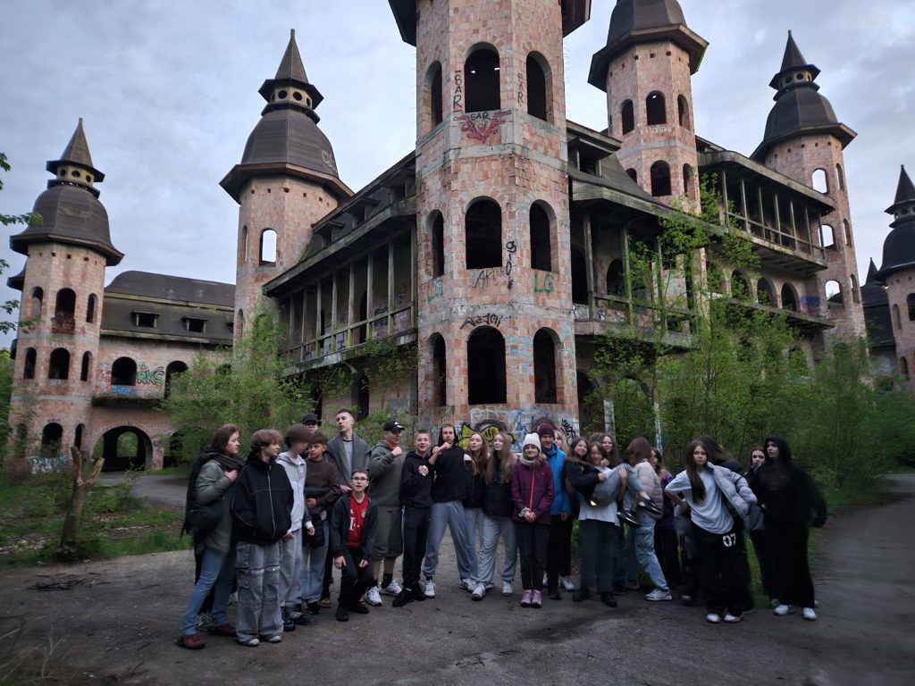 Na zdjęciu, na pierwszym planie uczestnicy wyprawy stoją na tle budowli z wieżyczkami