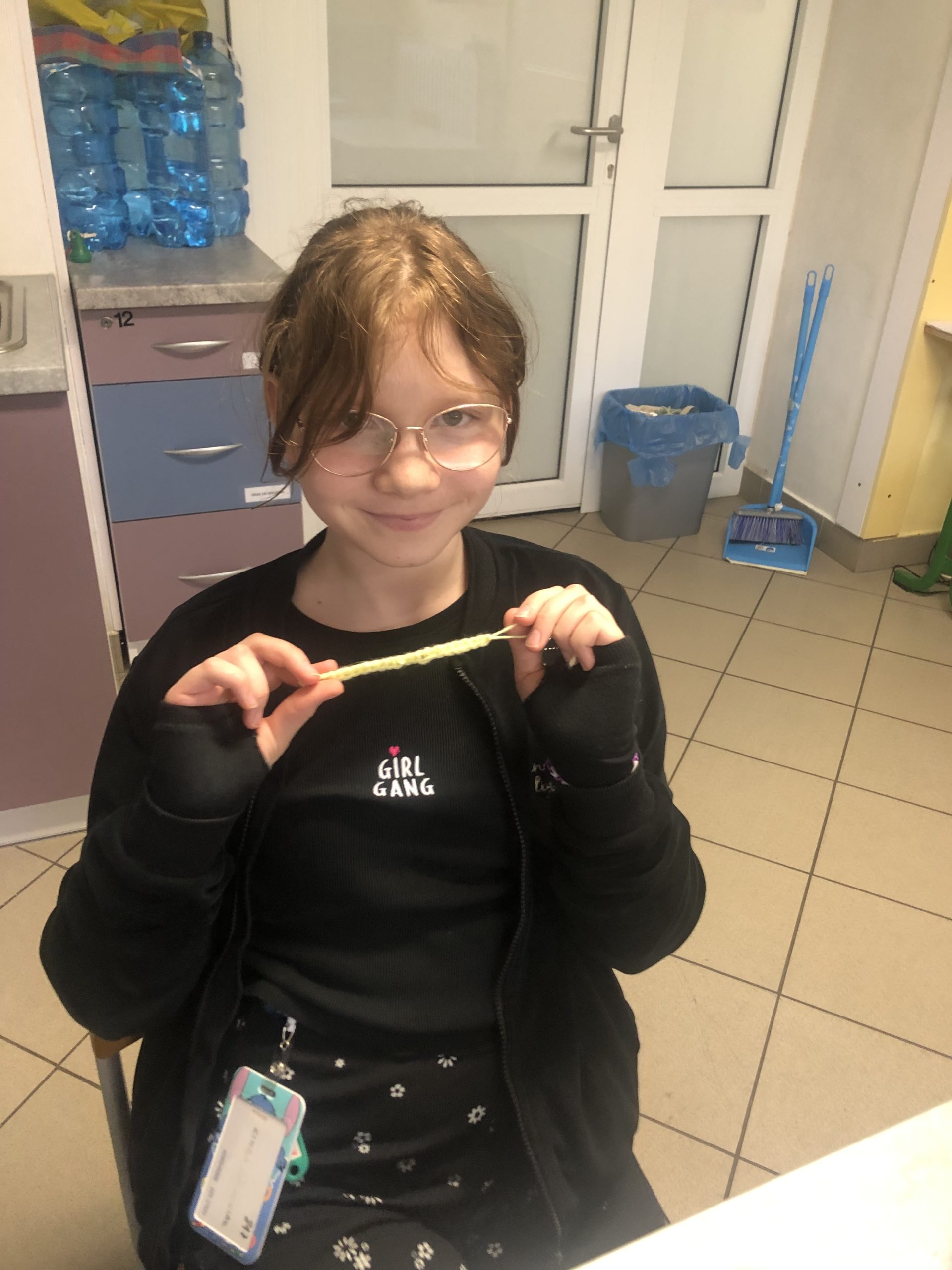 Dziewczynka prezentuje łańcuszek zrobiony na szydełku.