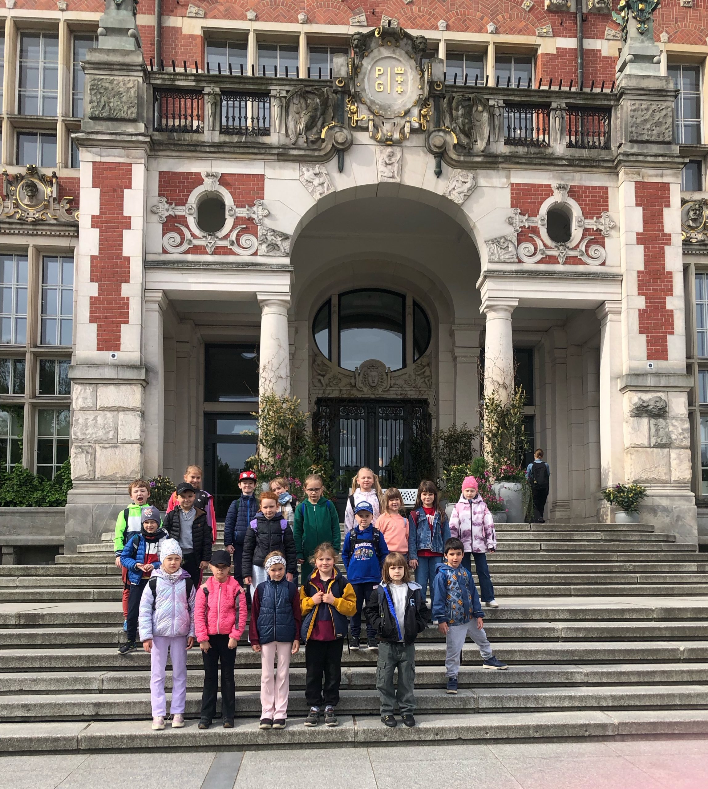 Grupa 19 dzieci stoi na schodach przed gmachem głównym Politechniki Gdańskiej.