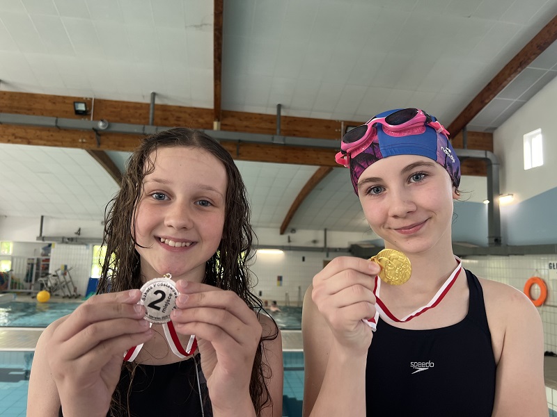 Dwie uczennice z medalami trzymanym w dłoniach pozuje do zdjęcia
