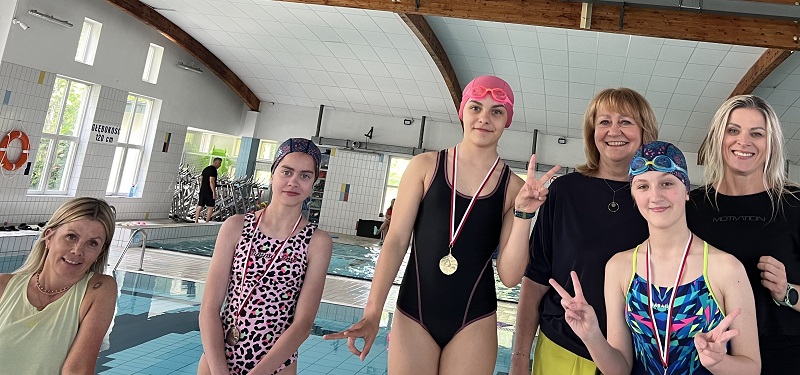 Trzy uczennice i trzy panie pozują do zdjęcia po dekoracji na tle niecek basenowych