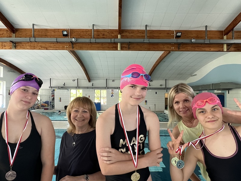 Trzy uczennice z medalami a tyłu miedzy nimi dwie uśmiechnięte panie