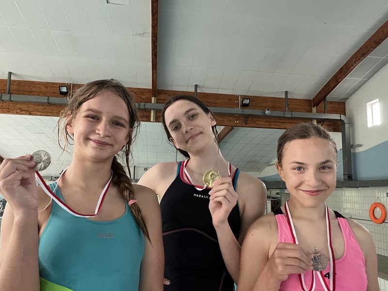 Trzy uczennice z medalami na piersiach pozują do zdjęcia