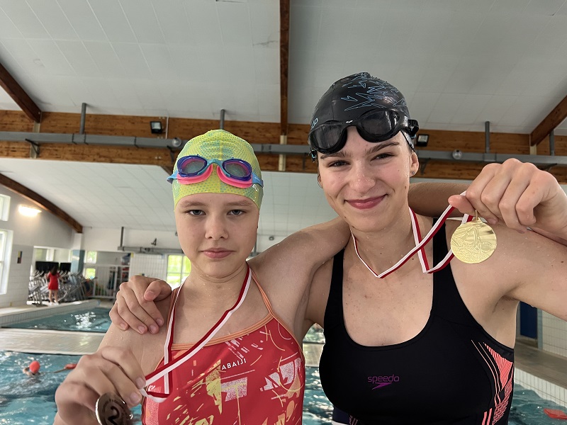 Dwie uczennice z medalami na piersiach pozują do zdjęcia