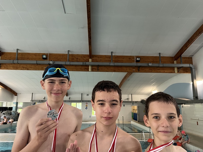 Trzech uczniów z medalami na piersiach pozują do zdjęcia