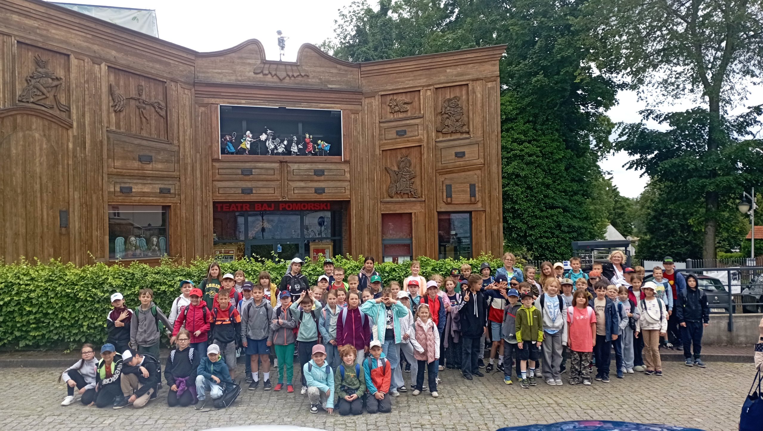 Trzy klasy trzecie stoją przed budynkiem Teatru Baj Pomorski.