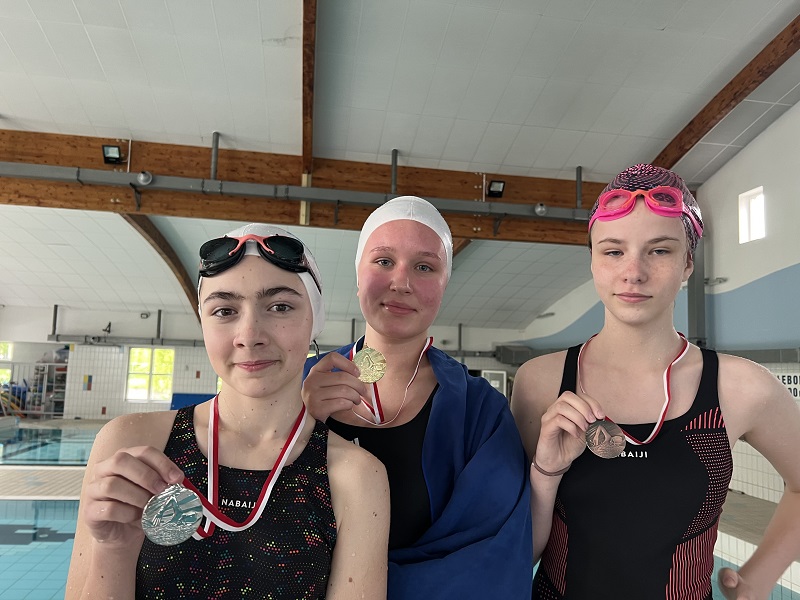 Trzy uczennice z medalami na piersiach pozują do zdjęcia