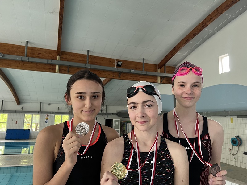 Trzy uczennice z medalami na piersiach pozują do zdjęcia