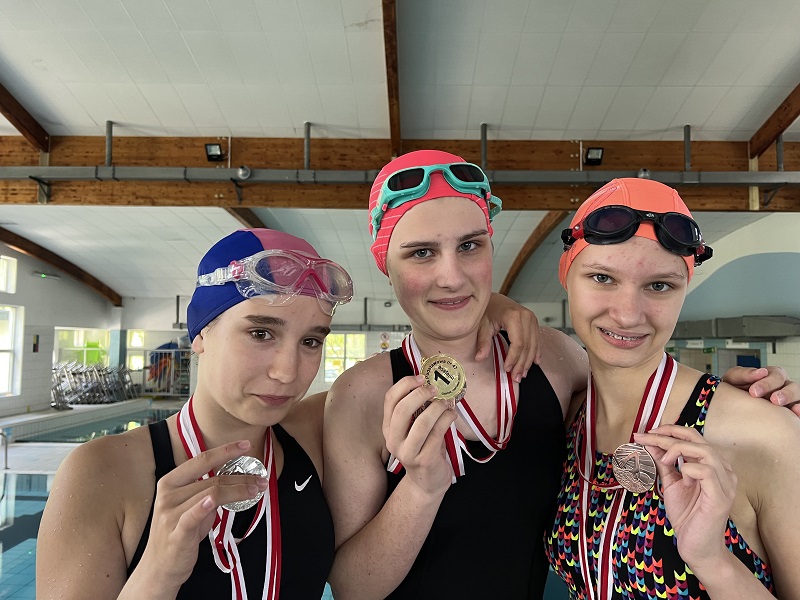 Trzy uczennice z medalami w dłoni pozuje do zdjęcia