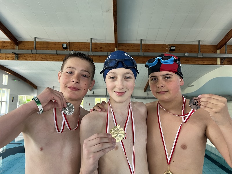 Trzech uczniów z medalami w dłoni pozuje do zdjęcia