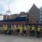 Na tle statku Sołdek oraz budynku Muzeum Morskiego nad Motławą pozują do zdjęcia uczniowie klasy 1c.