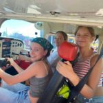 Trzy uśmiechnięte dziewczynki siedzą w środku samolotu Awionetki