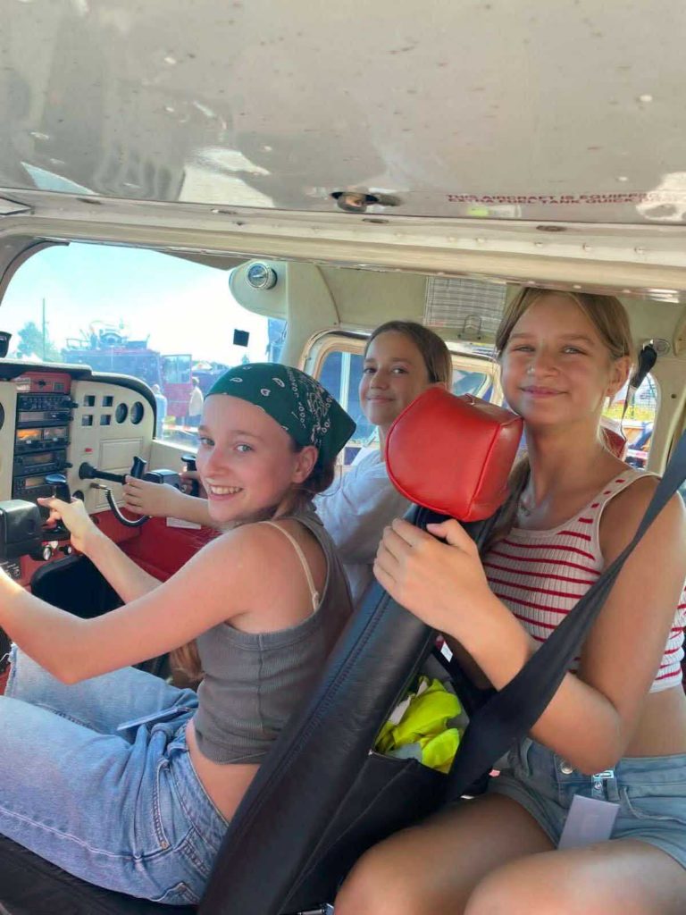 Trzy uśmiechnięte dziewczynki siedzą w środku samolotu Awionetki